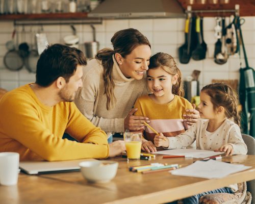 happy-parents-enjoying-with-their-small-daughters-who-are-coloring-paper-home